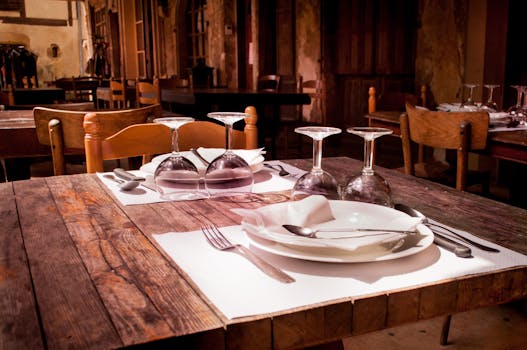 A rustic restaurant table set with wine glasses and cutlery invites guests to dine.